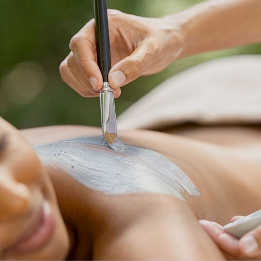 A person receives a spa treatment, with a brush applying a gray mask on their back. The person is smiling and appears relaxed. A towel covers part of their body, creating a soothing and calming atmosphere. 124 on Queen Hotel and Spa | Hotel & Spa Niagara-on-the-lake | 1 (855) 988-4552 A person receives a spa treatment, with a brush applying a gray mask on their back. The person is smiling and appears relaxed. A towel covers part of their body, creating a soothing and calming atmosphere. 124 on Queen Hotel and Spa | Hotel & Spa Niagara-on-the-lake | 1 (855) 988-4552